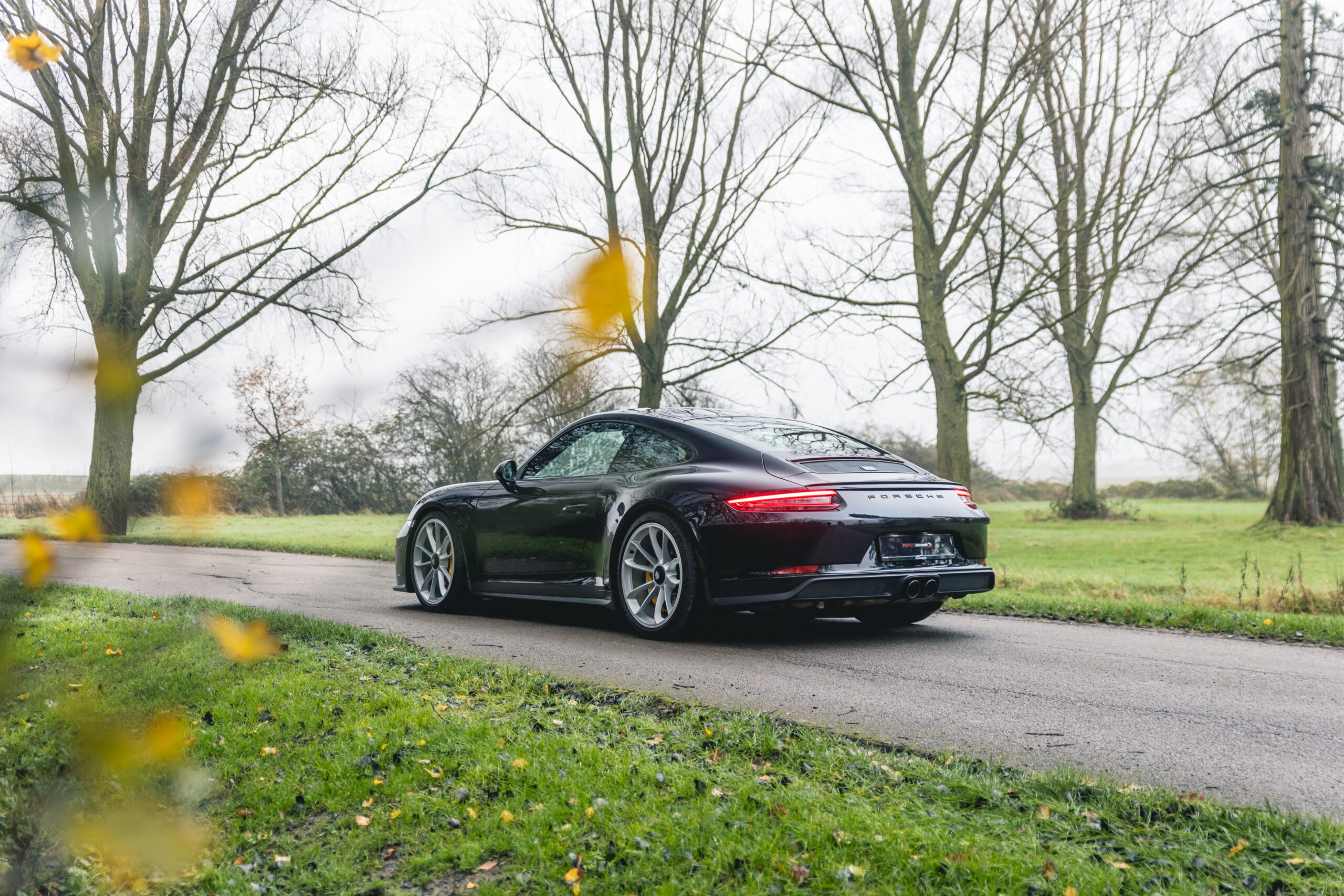 black porsche driving through trees