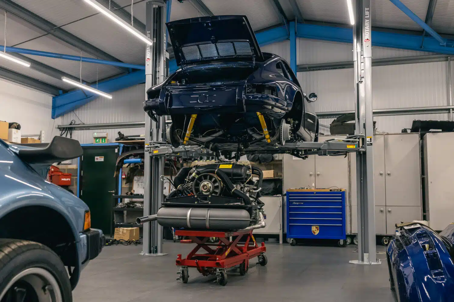 blue porsche with engine removed in a workshop